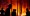 Forest fire at night with silhouetted fire fighter against burning forest.