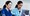 two medical staff in scrubs doing administrative tasks on a laptop.
