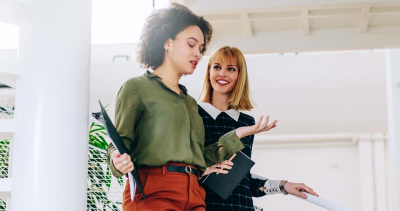 Two female colleagues talking as they walk down stairs