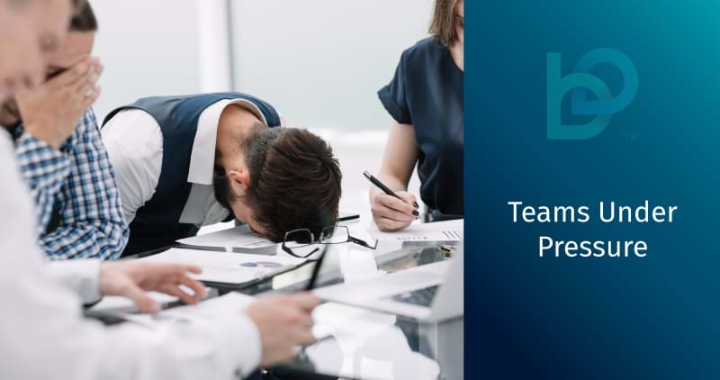 A colleague lowers his face to the table during an ineffective and boring team meeting