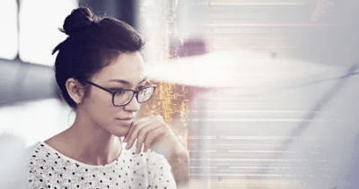 A young woman is sitting in her office at her desk deep in thought