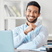 A smiling bearded young man sitting at his work station and smiling