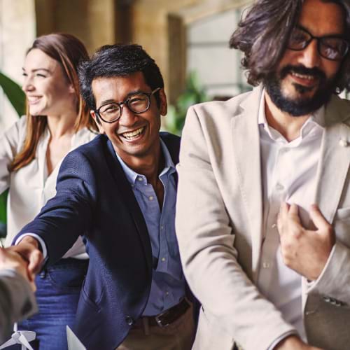 Work colleagues greeting each other with hearty handshakes and warms smiles
