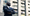 A business man with arms folded standing in the street is looking up into the sky.