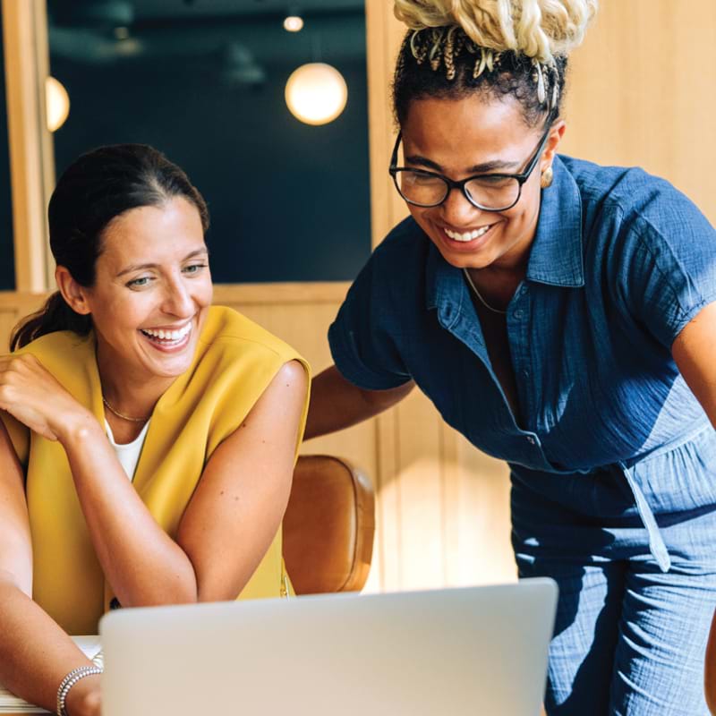 Two women looking at a computer screen and smiling